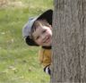 Jonathan peeks from behind a tree